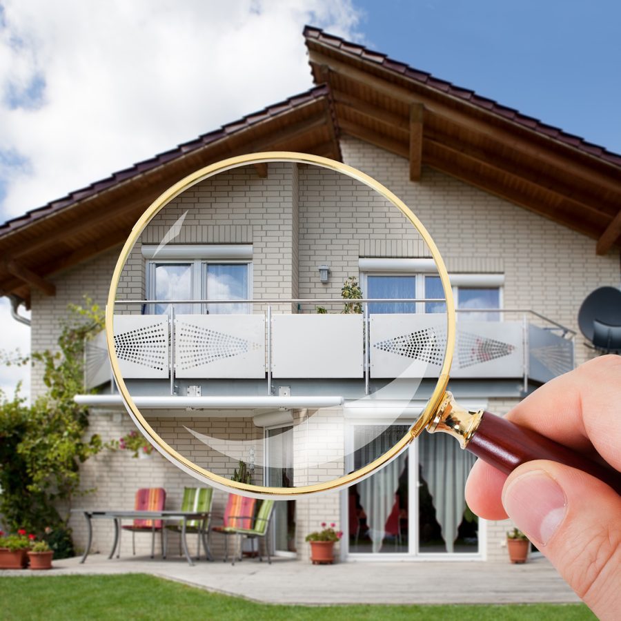 Person Hand With Magnifying Glass Over Luxury House